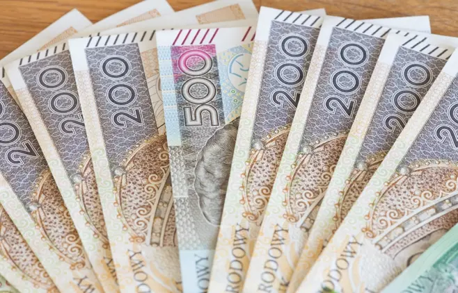 Wachlarz ułożony z polskich banknotów na drewnianym stole.